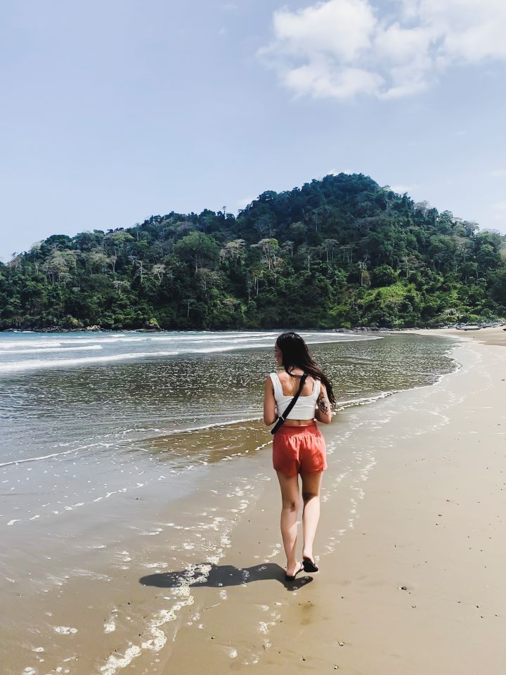 ruta por indonesia chica caminando por la playa y selva de fondo